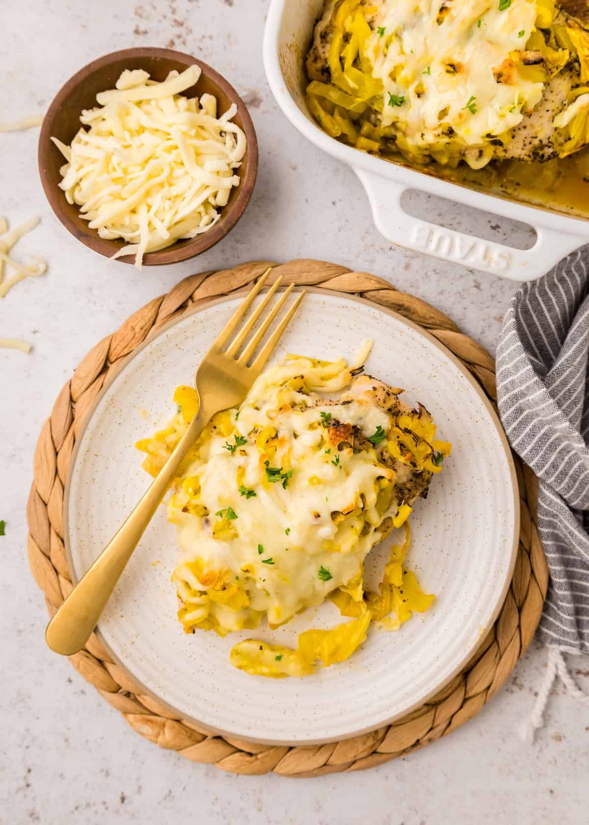 Banana Pepper Chicken breast topped with melted cheese, served with a fork and shredded cheese.