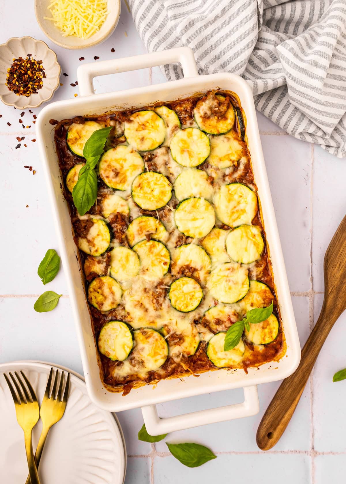 Beef Zucchini Casserole in a casserole dish with fresh basil leaves.
