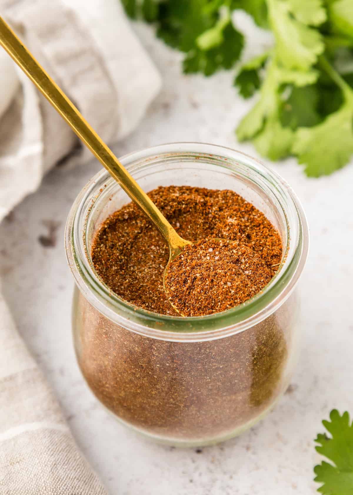 Taco Seasoning in jar with gold spoon.