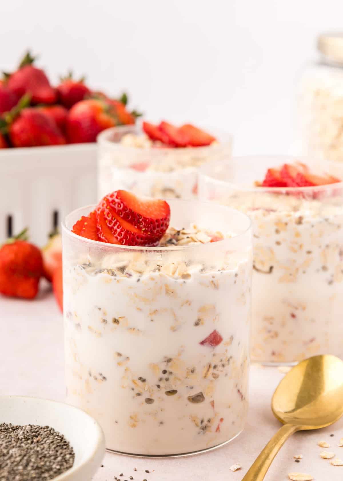 Strawberry overnight oats in glasses, topped with fresh strawberries.