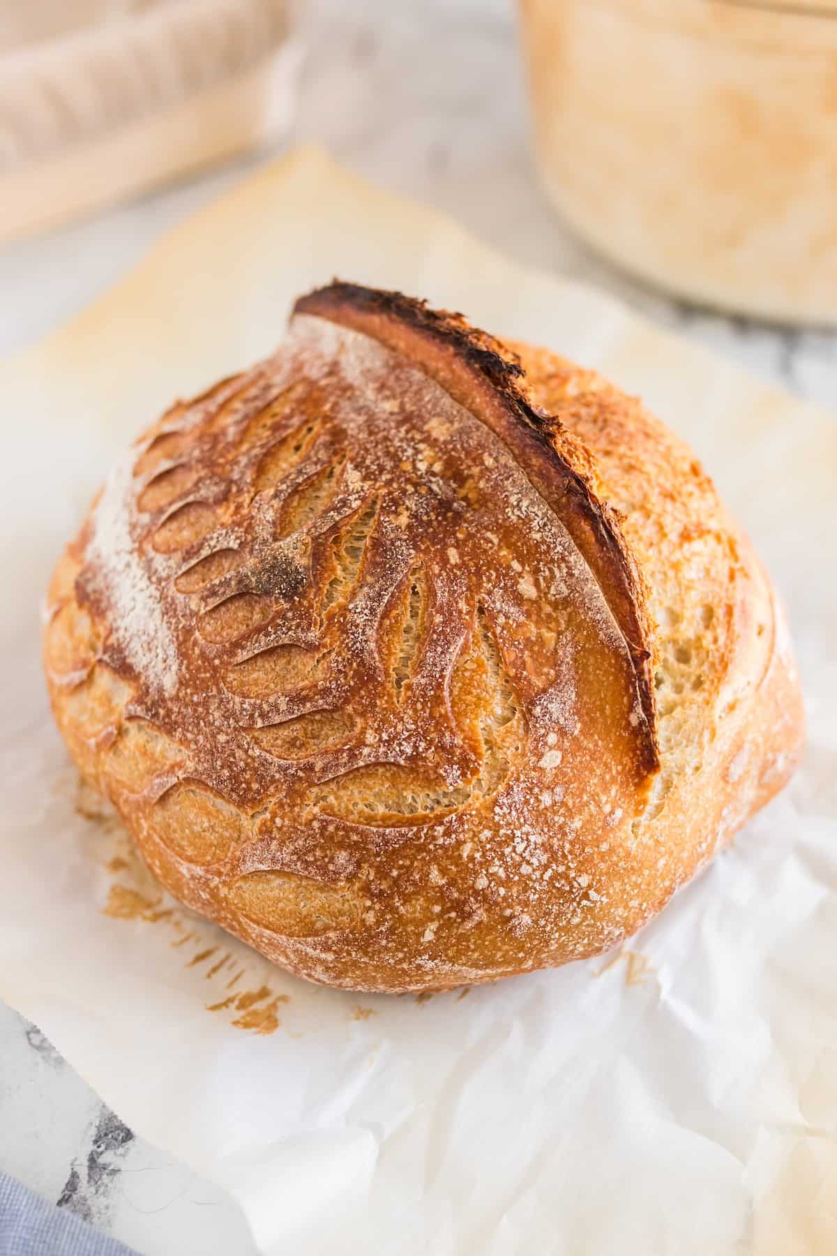 A loaf of sourdough bread with decorative scoring patterns on the top.