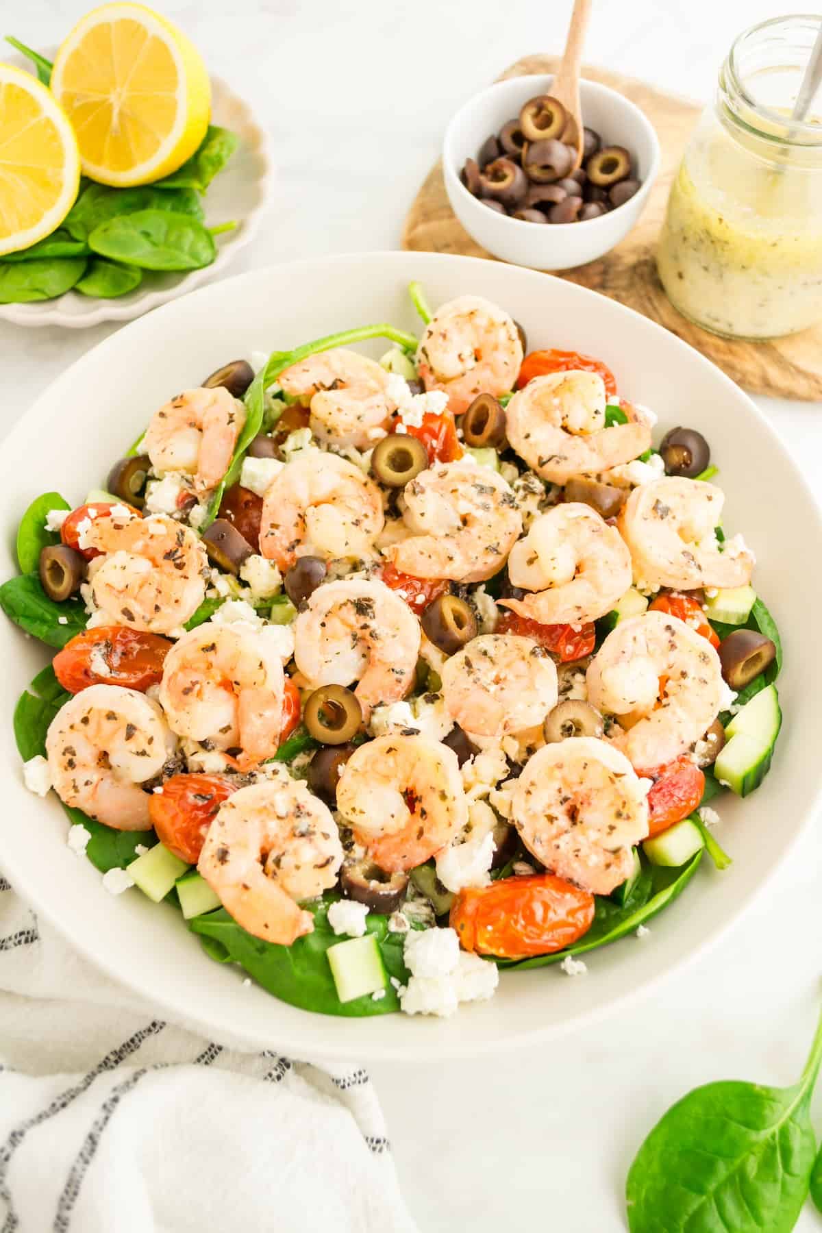 Greek shrimp salad served in bowl with dressing and olives.