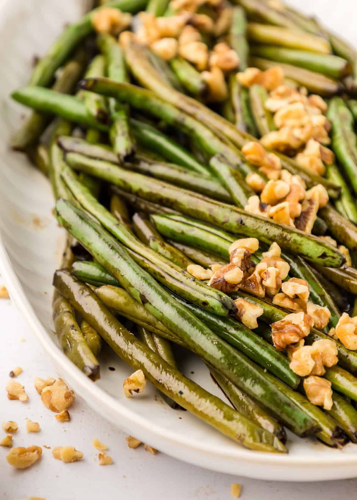 Balsamic Green Beans topped with chopped walnuts on a white plate.