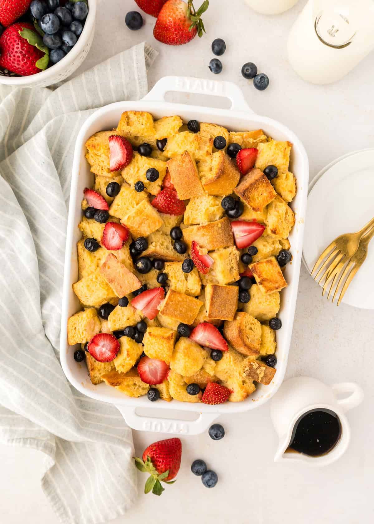 Berry French Toast Casserole topped with strawberries and blueberries in a white dish.
