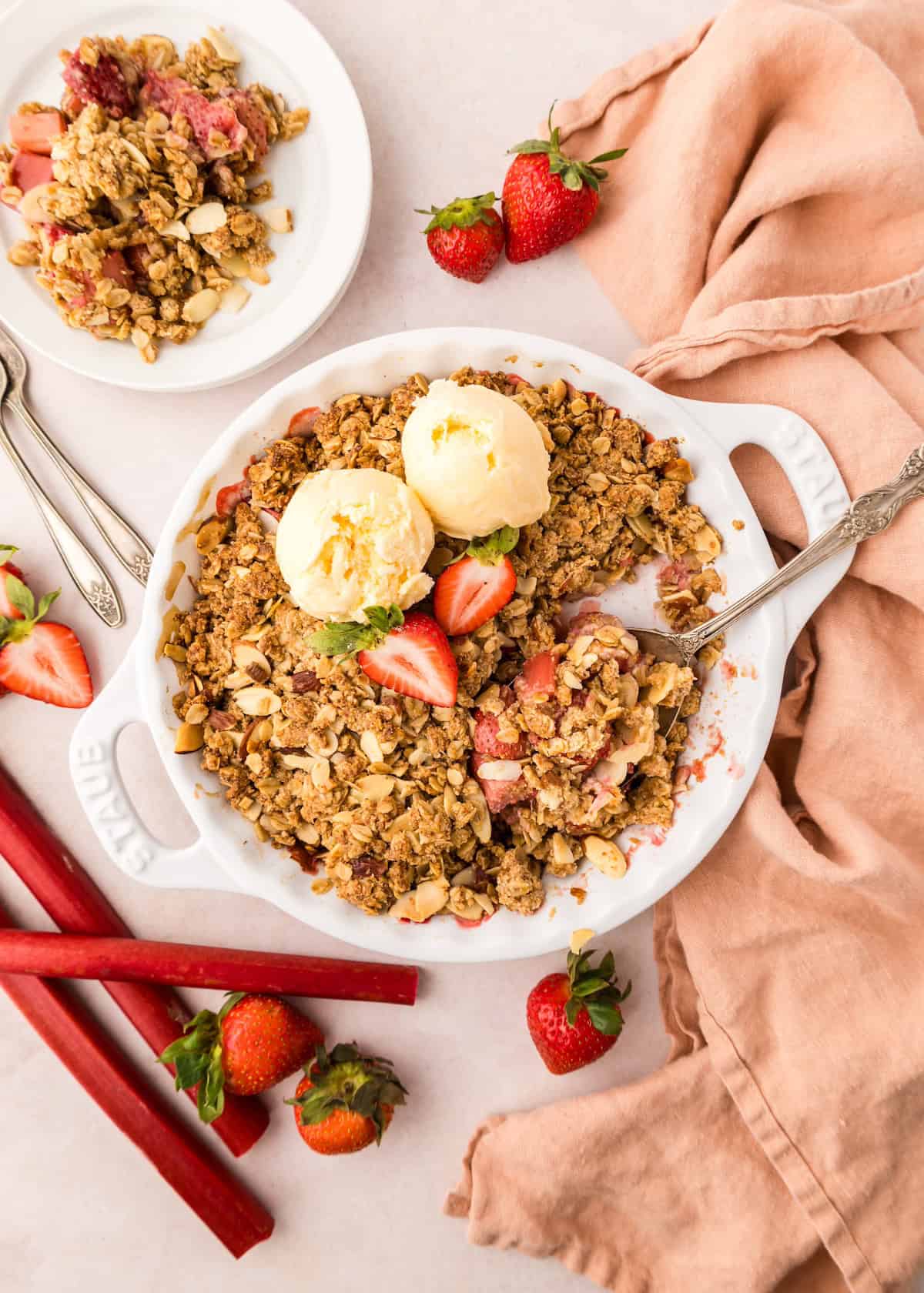 strawberry rhubarb crisp in pie dish with ice scream and strawberry