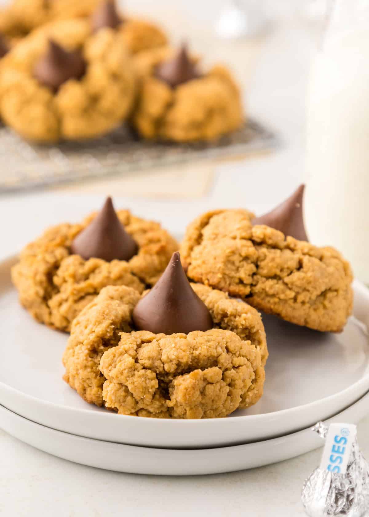 Three Gluten-Free Peanut Butter Blossoms with chocolate kisses on a white plate.