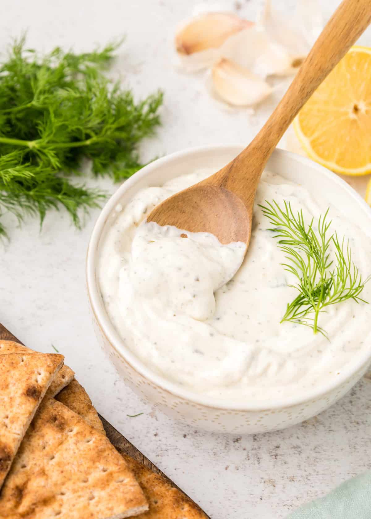 Tzatziki Sauce with dill and a wooden spoon.