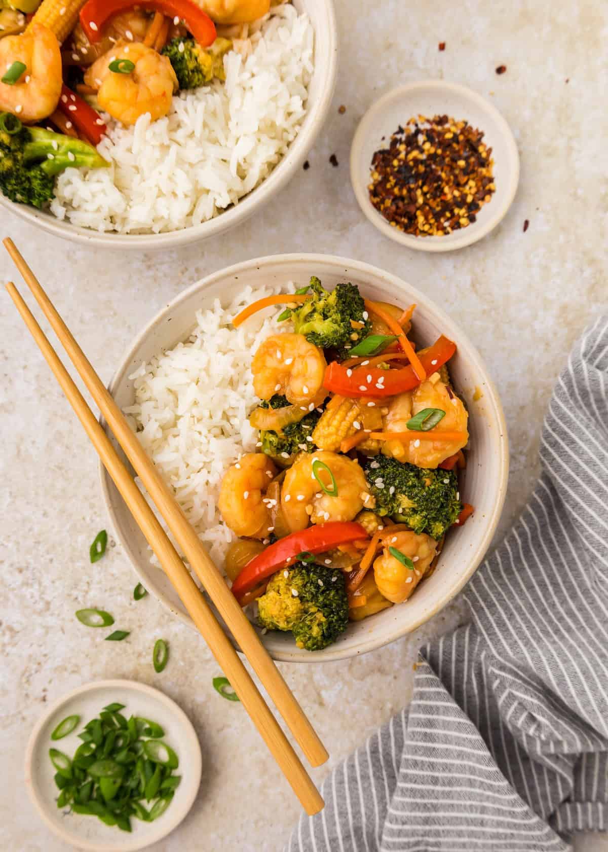 Shrimp Stir Fry bowl with rice, broccoli, peppers, and chopsticks on the side.