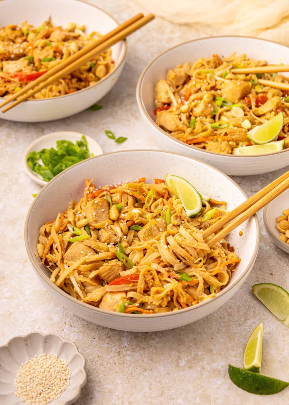 Bowls of Chicken Pad Thai, with chopsticks wrapped around the noodles.