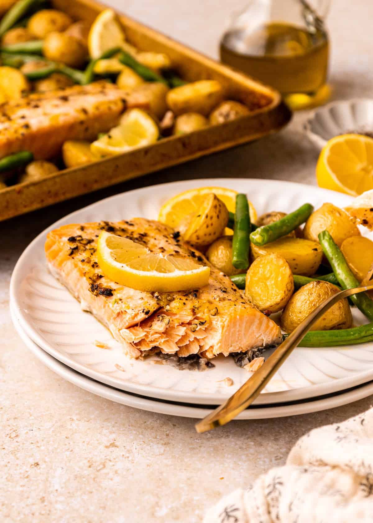 Sheet Pan Lemon Pepper Salmon with potatoes and green beans on a white plate with a fork.