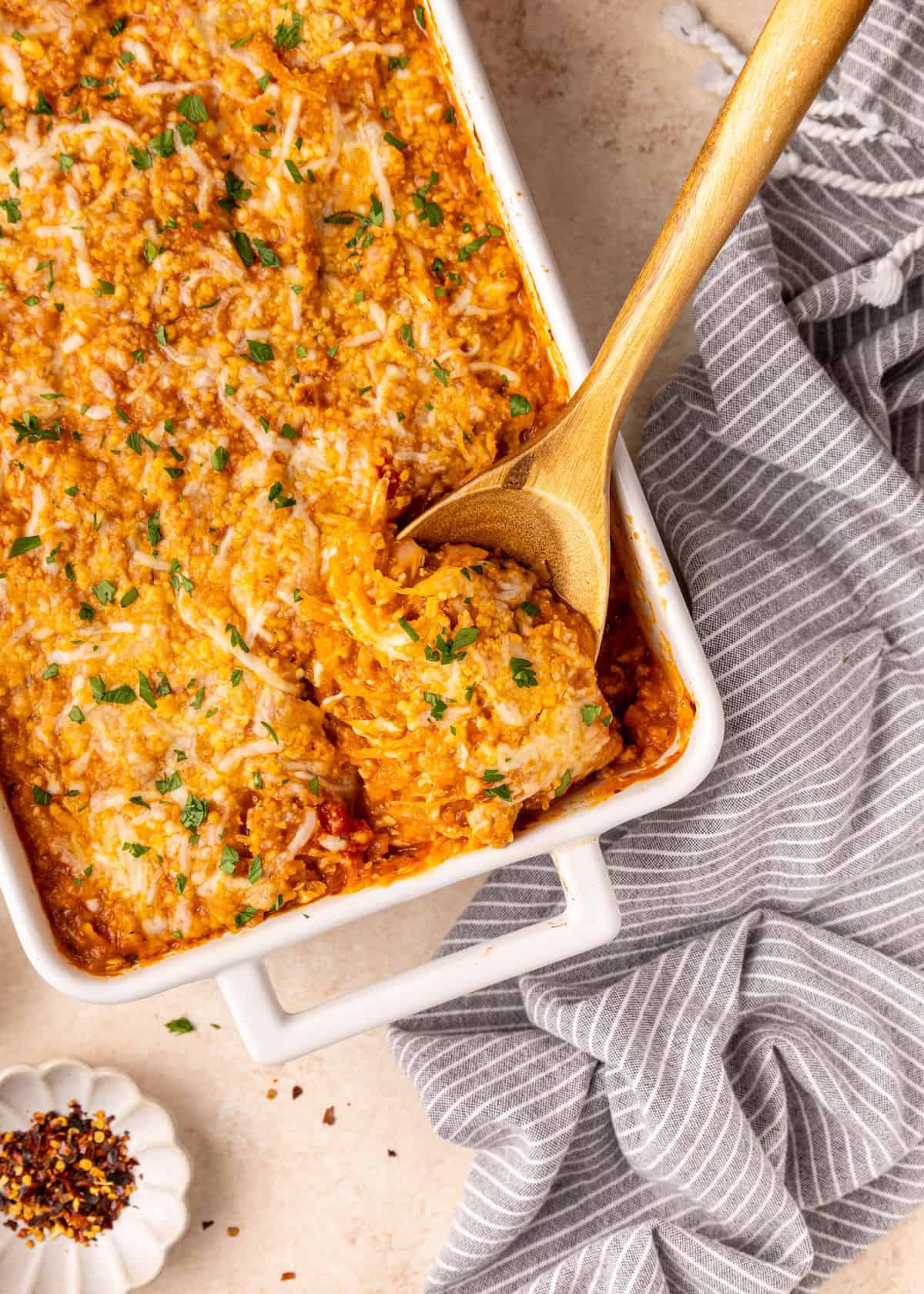 Spaghetti Squash Casserole baked in a white dish, served with a wooden spoon.