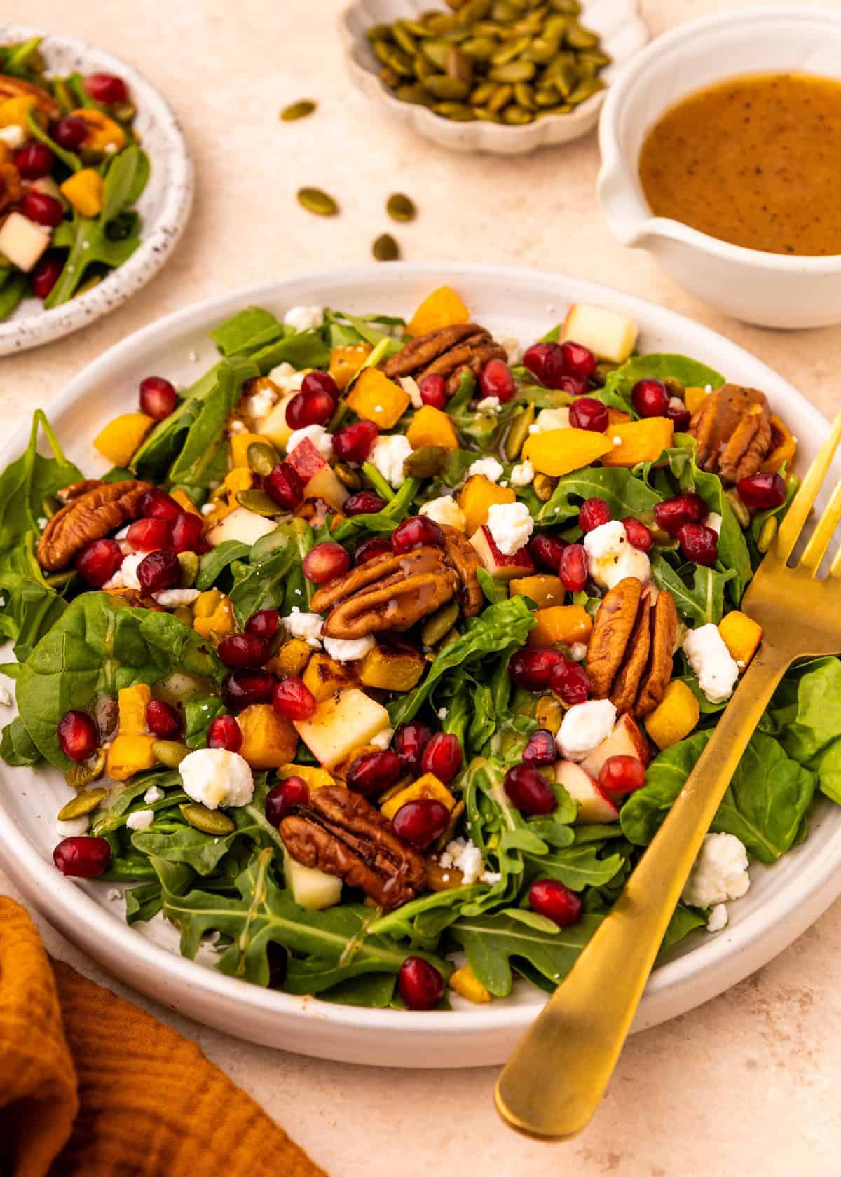 Fall Harvest Salad with arugula, pecans, pomegranate seeds, goat cheese, and vinaigrette.