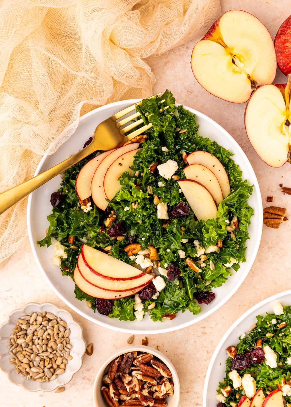 Kale Apple Salad with pecans, feta, cranberries, and a gold fork on the side.