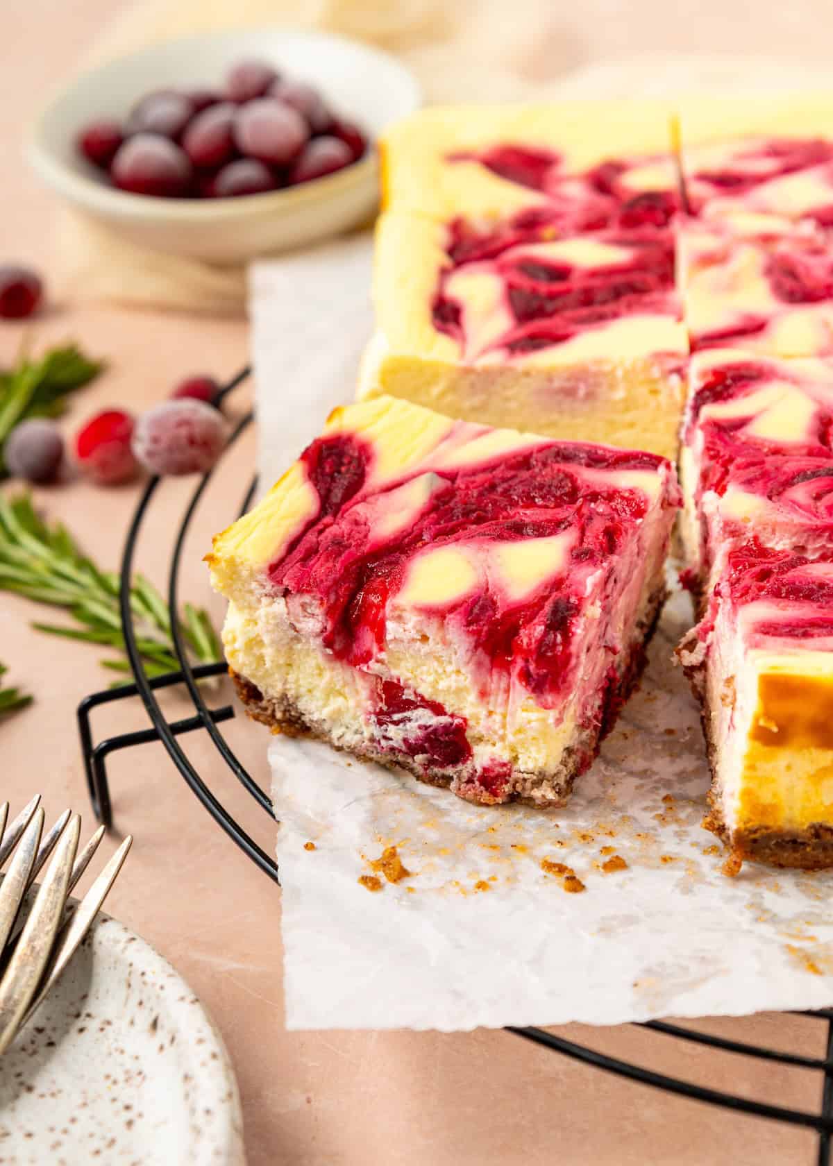 Cranberry Cheesecake Bars on parchment, one piece slightly pulled out for a tempting look.