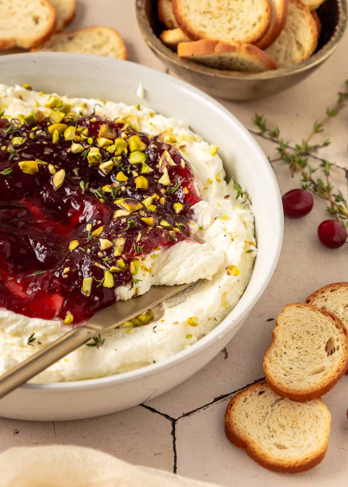Cranberry Whipped Feta Dip with cranberry sauce, crushed pistachios, and bread to dip.